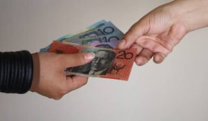 hands of two women paying and receiving Australian banknotes